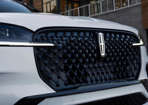 The black grille of a white 2025 Lincoln Aviator® SUV is shown with its fog lights on. | J.C. Lewis Lincoln in Savannah GA