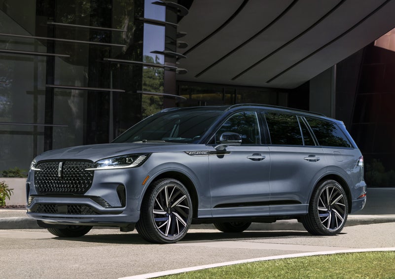A gray 2025 Lincoln Aviator® SUV is parked outside a modern building showcasing the driver’s side of the vehicle. | J.C. Lewis Lincoln in Savannah GA