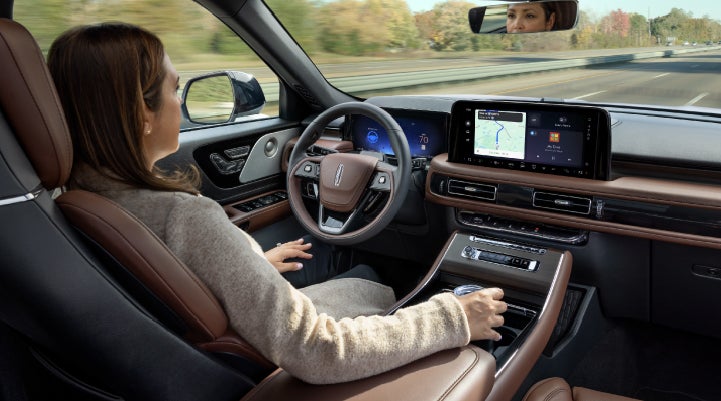 A 2027 Lincoln Aviator® SUV is being driven hands-free on a highway lined with trees. | J.C. Lewis Lincoln in Savannah GA