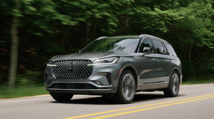 A 2027 Lincoln Aviator® SUV is being driven down a road lined with trees. | J.C. Lewis Lincoln in Savannah GA