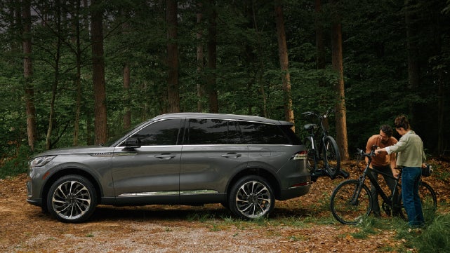A father and son load e-bikes on a bike rack attached to a 2027 Lincoln Aviator® SUV. | J.C. Lewis Lincoln in Savannah GA